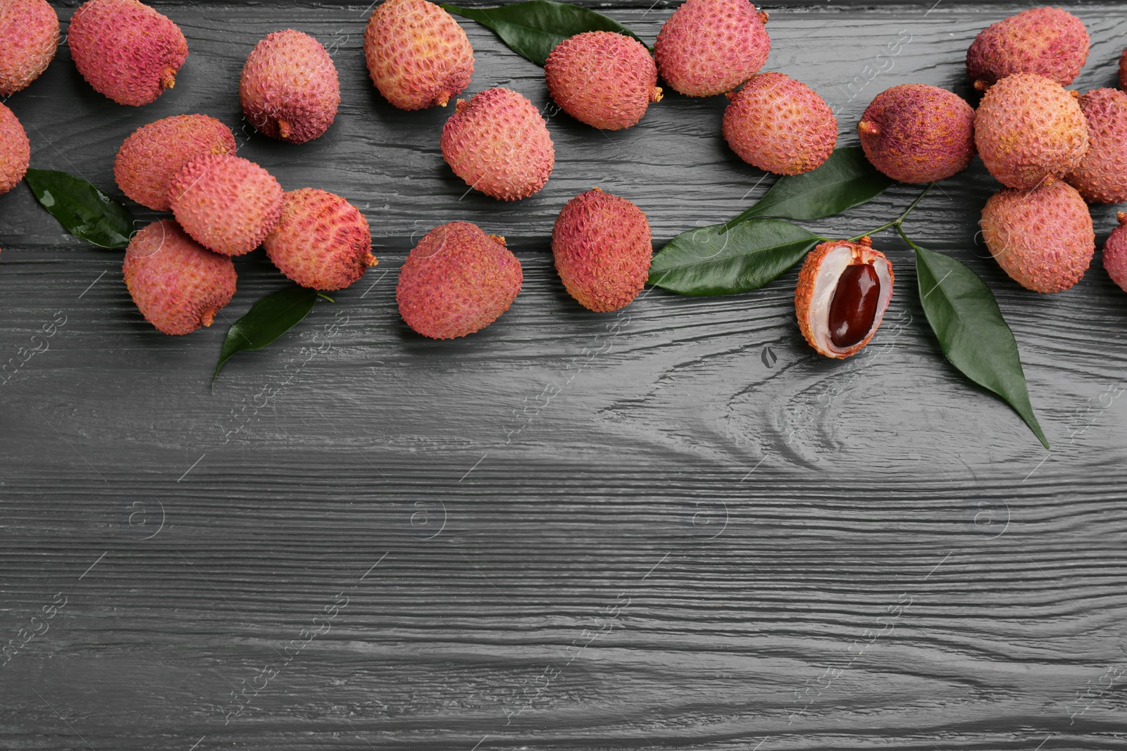 Photo of Fresh ripe lychee fruits on grey wooden table, flat lay. Space for text