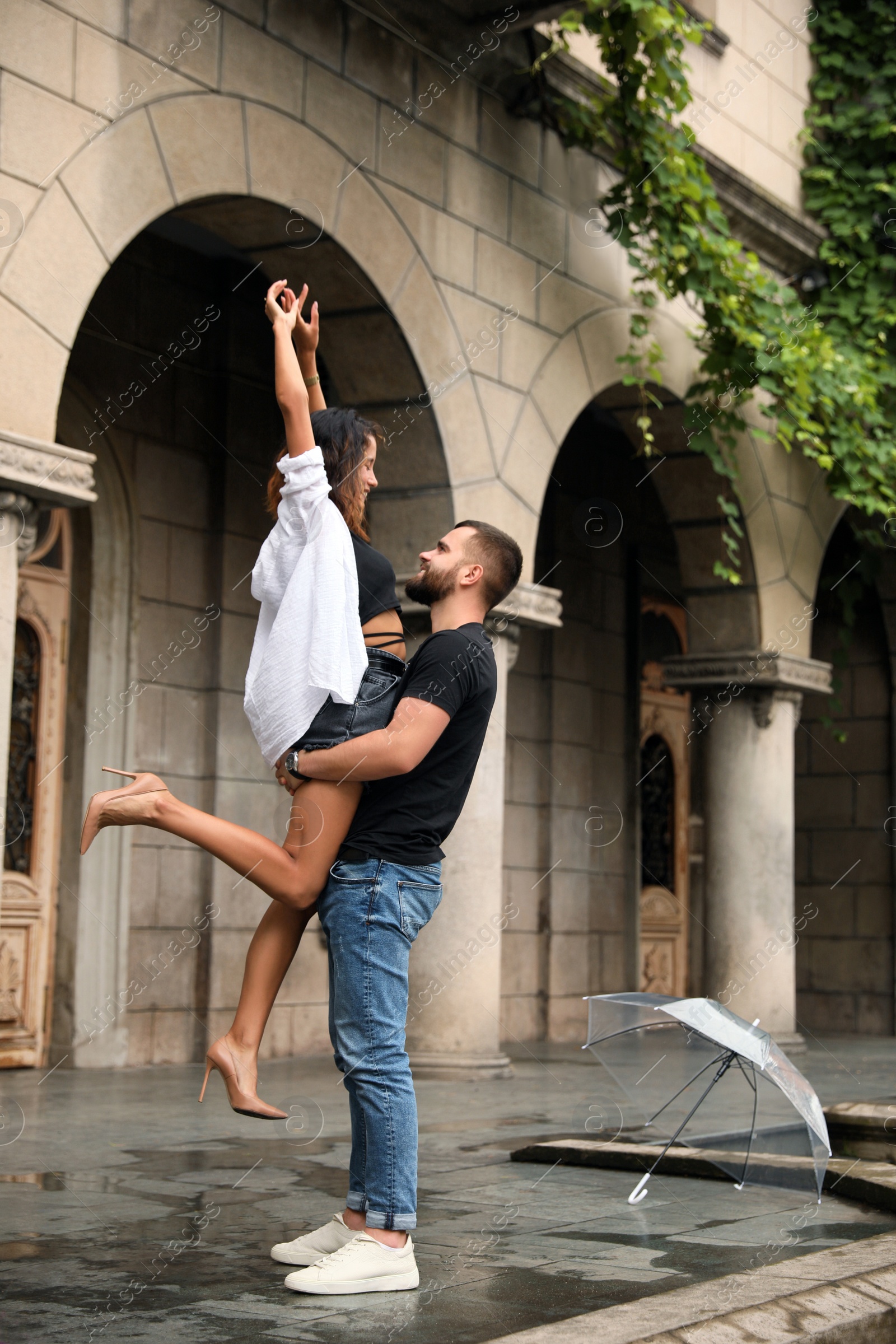 Photo of Young couple enjoying time together under rain on city street