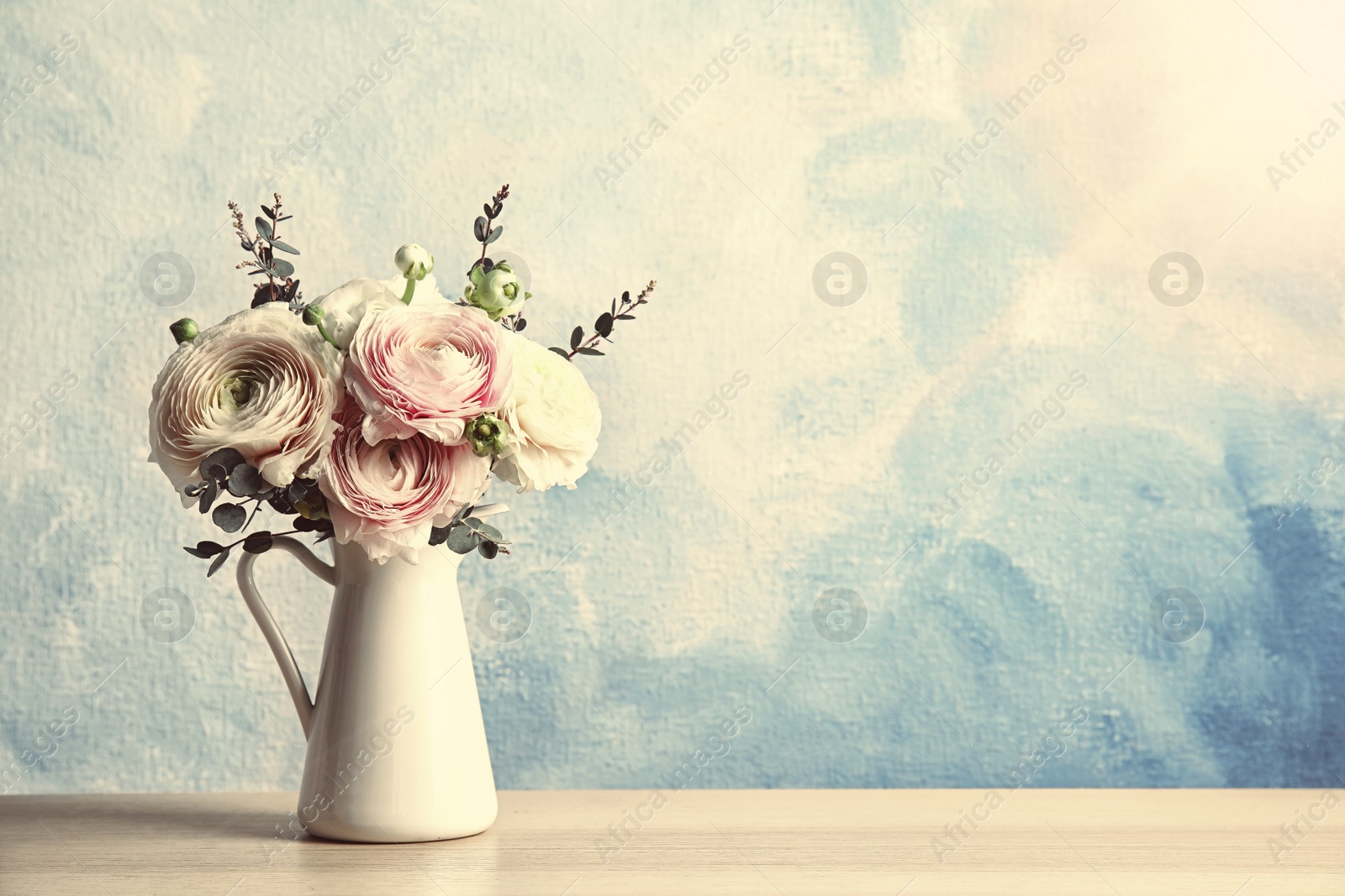 Image of Vase with beautiful spring ranunculus flowers on white wooden table. Space for text