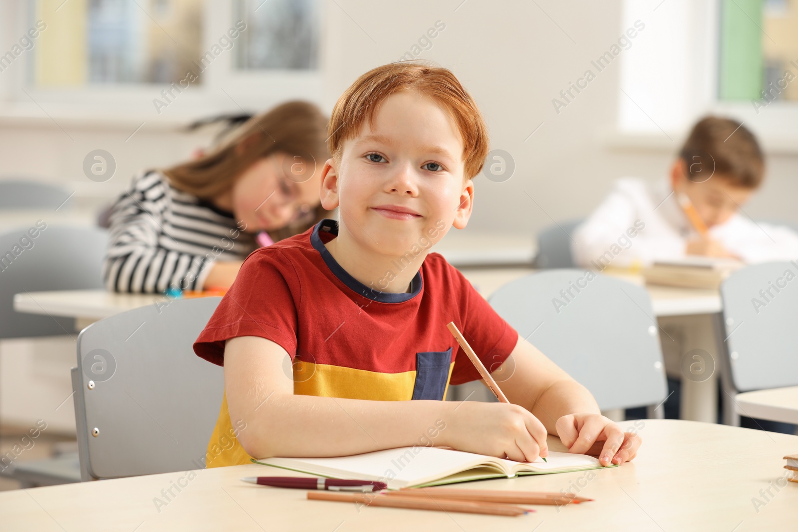 Photo of Portrait of cute little boy studying in classroom at school