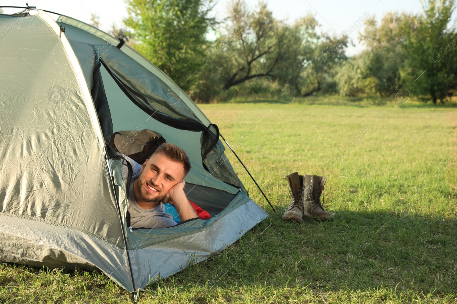 Photo of Young man lying inside camping tent on sunny day