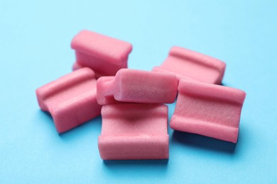 Photo of Tasty pink chewing gums on light blue background, closeup