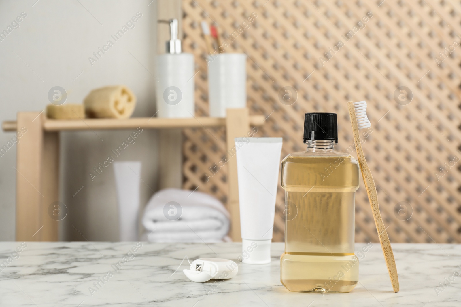 Photo of Mouthwash and other oral hygiene products on white marble table in bathroom, space for text