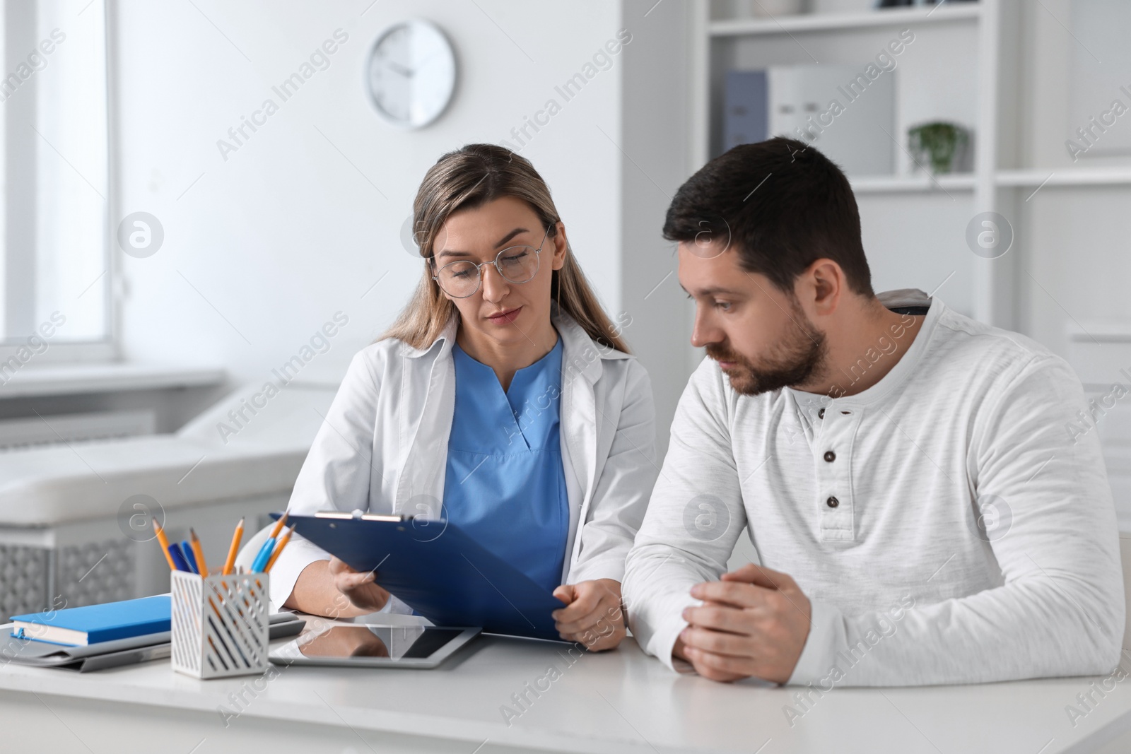 Photo of Professional doctor working with patient at white table in hospital