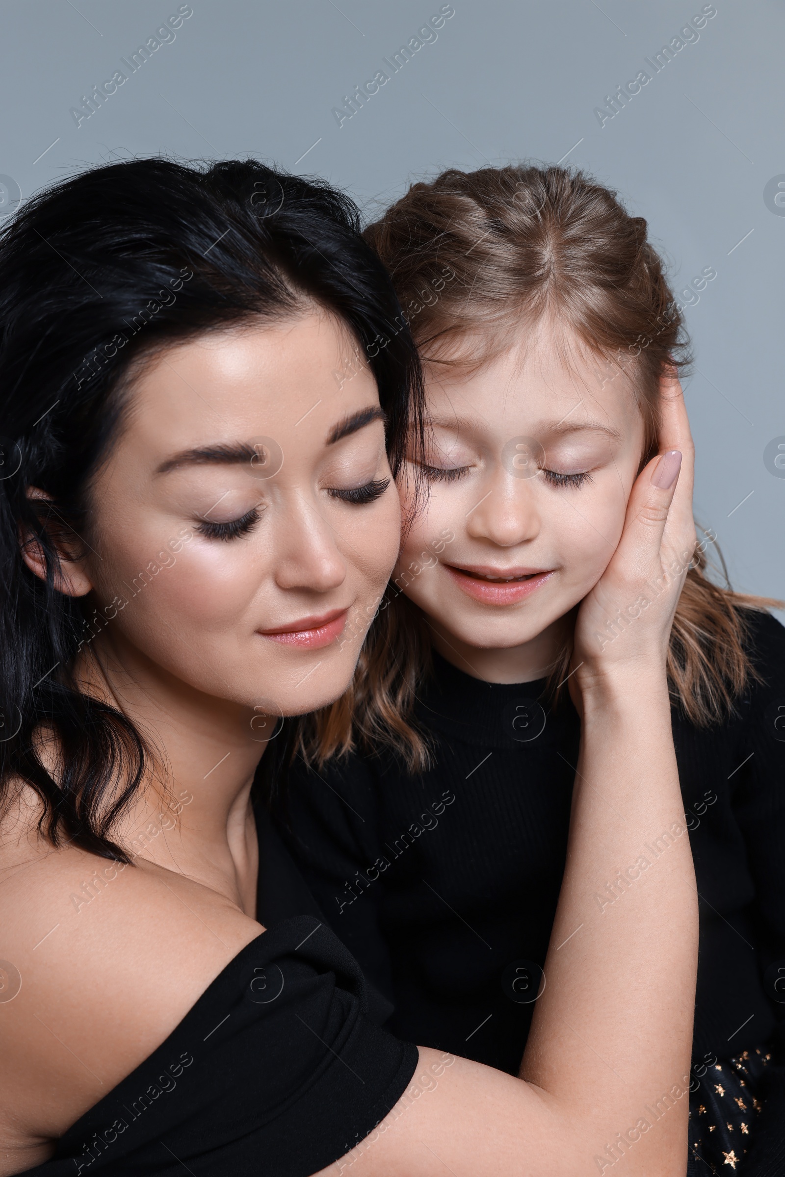 Photo of Beautiful mother with little daughter on grey background