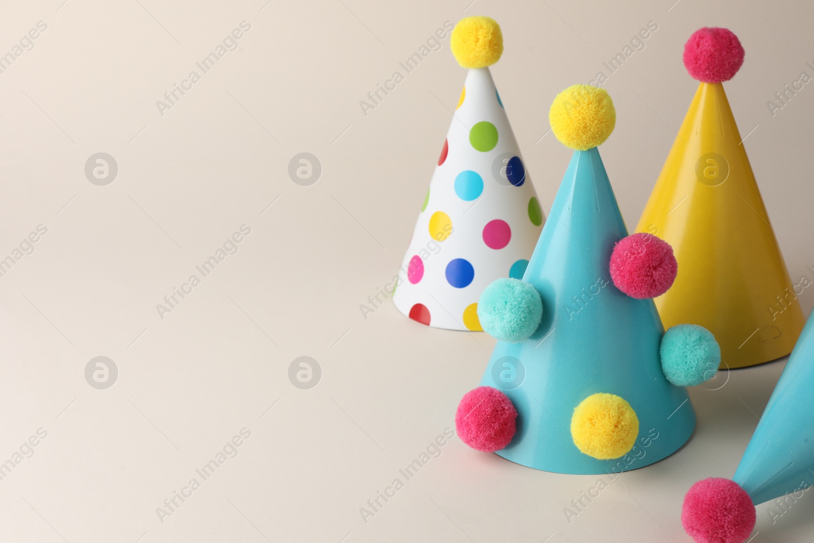 Photo of Colorful party hats with pompoms on beige background