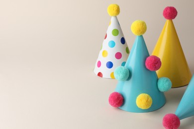 Photo of Colorful party hats with pompoms on beige background
