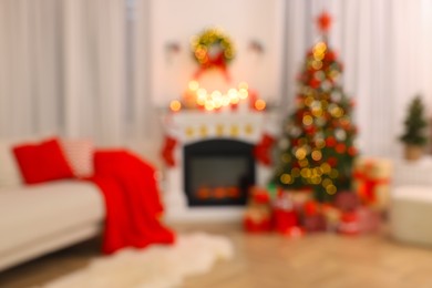 Photo of Blurred view of festively decorated room with Christmas tree, fireplace and sofa. Interior design