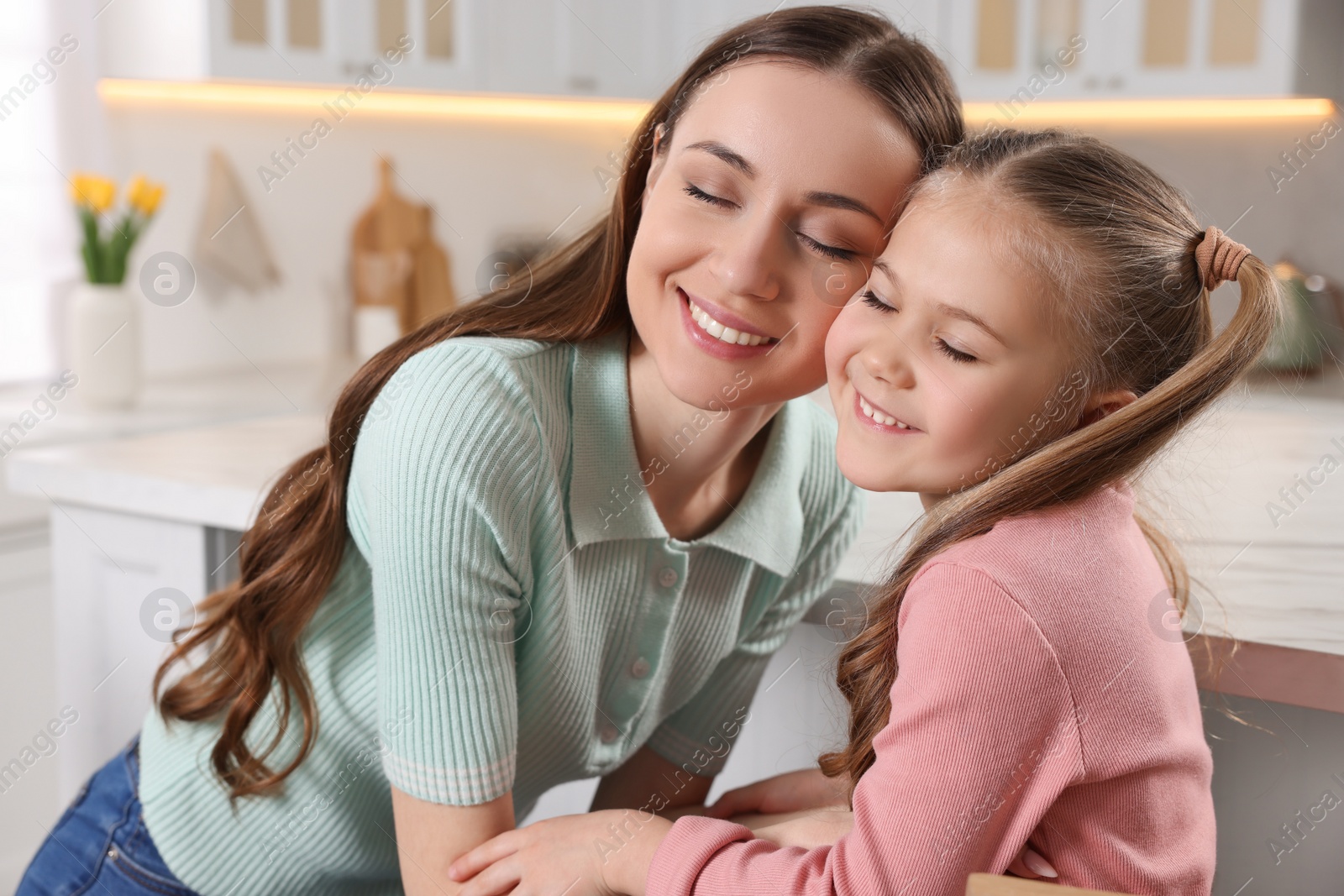 Photo of Happy mother with her cute daughter in kitchen