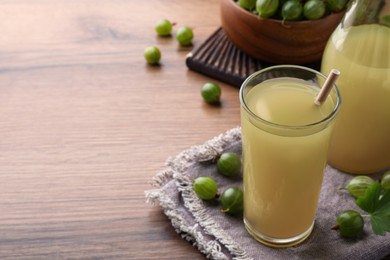 Tasty gooseberry juice on wooden table. Space for text