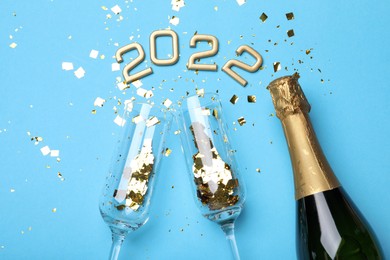 Photo of Happy New Year 2022! Flat lay composition with bottle of sparkling wine on light blue background