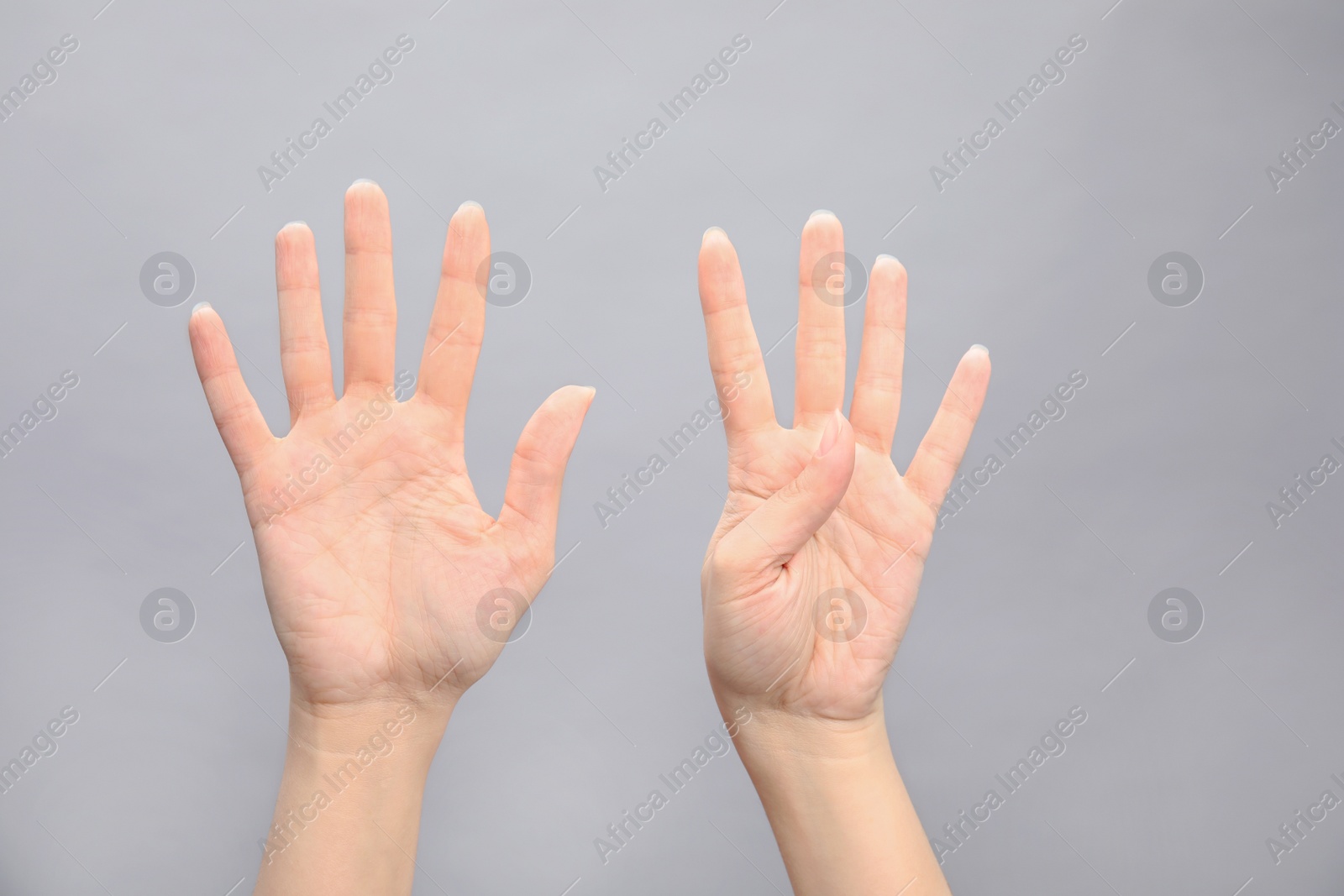 Photo of Woman showing sign nine on grey background, closeup. Body language