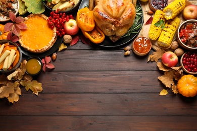 Photo of Traditional Thanksgiving day feast with delicious cooked turkey and other seasonal dishes served on wooden table, flat lay. Space for text