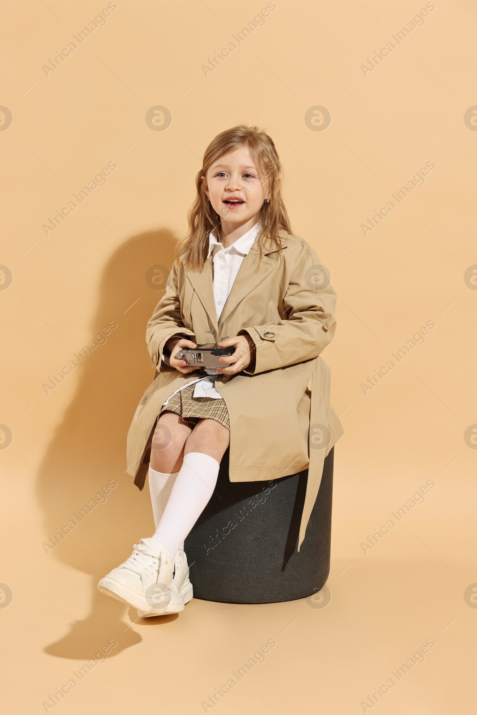 Photo of Fashion concept. Stylish girl with vintage camera on pale orange background
