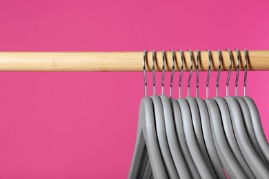 Photo of Wooden rack with clothes hangers on color background, closeup. Space for text