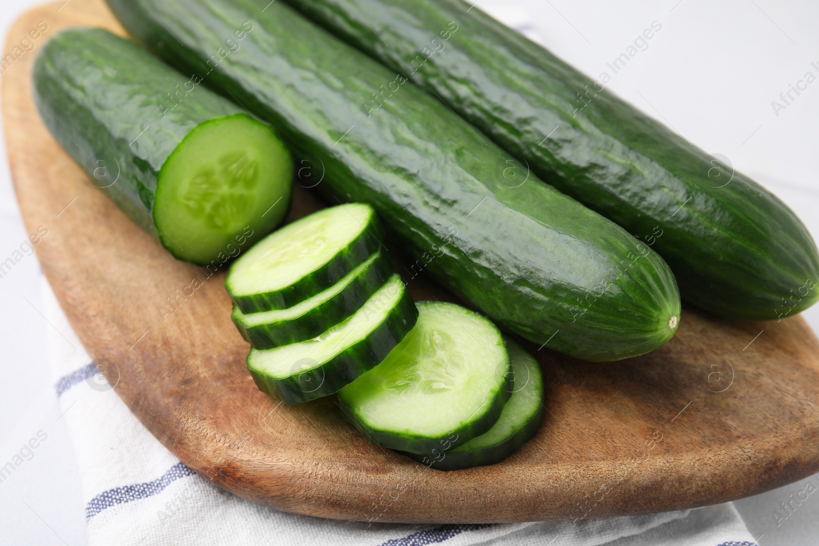 Photo of Fresh whole and cut cucumbers on white table, closeup