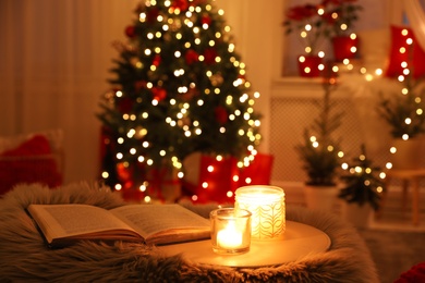 Photo of Book and candles in room with Christmas decorations. Interior design