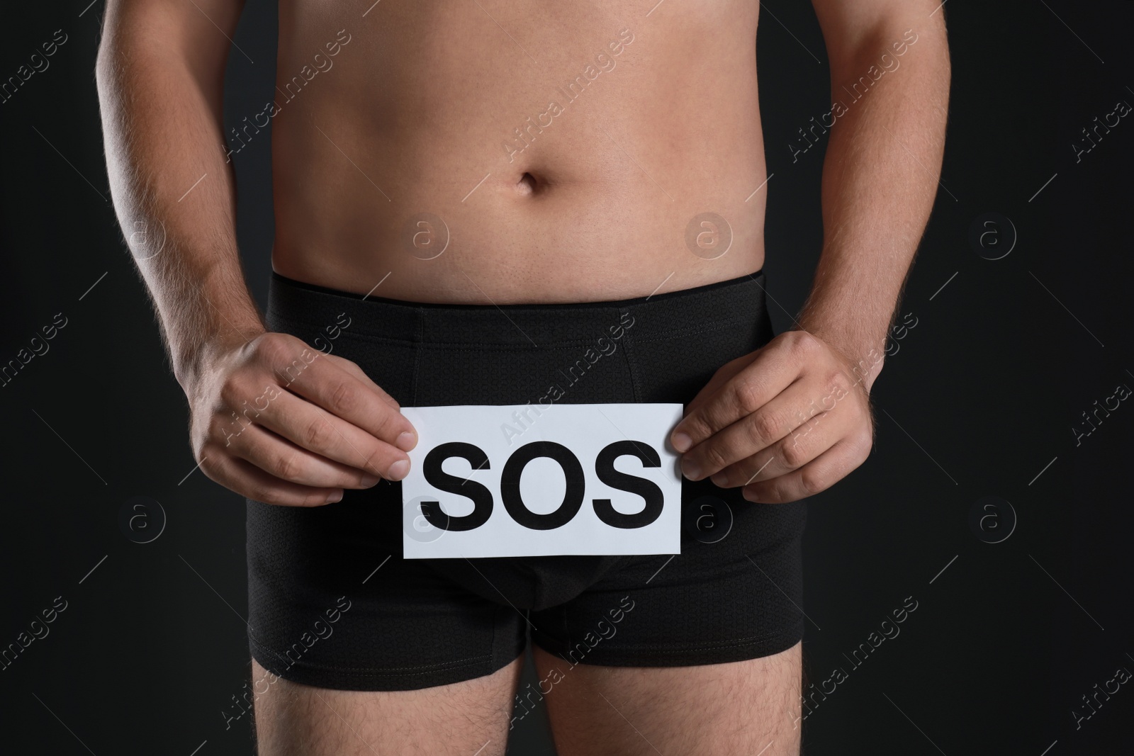 Photo of Man holding SOS sign on black background, closeup. Urology problems