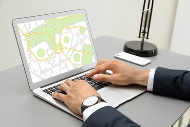 Image of Man analyzing cadastral map on laptop at table, closeup 