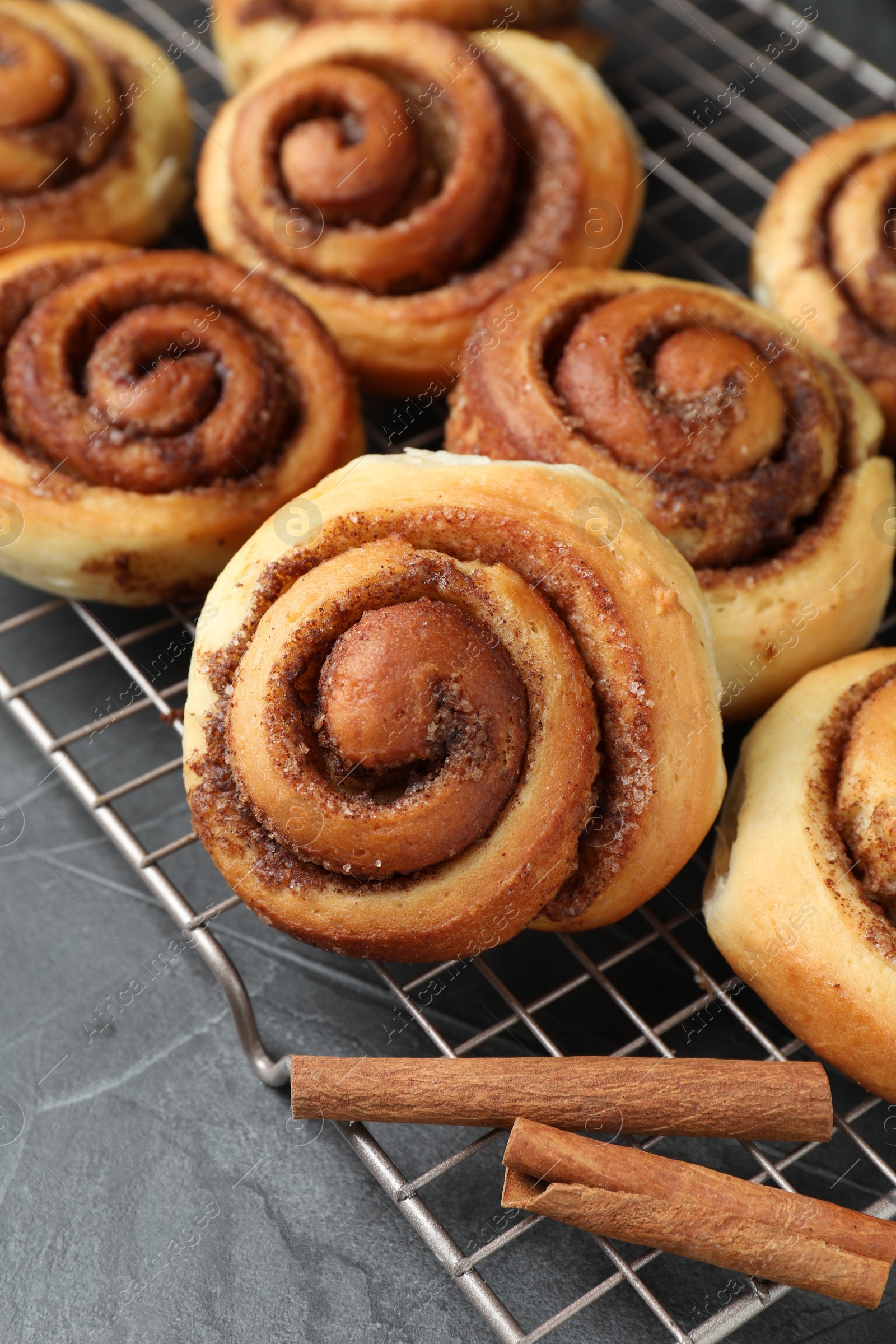 Photo of Tasty cinnamon rolls on black table, closeup