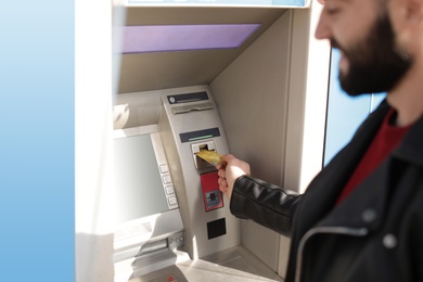 Photo of Man inserting credit card into cash machine outdoors, closeup