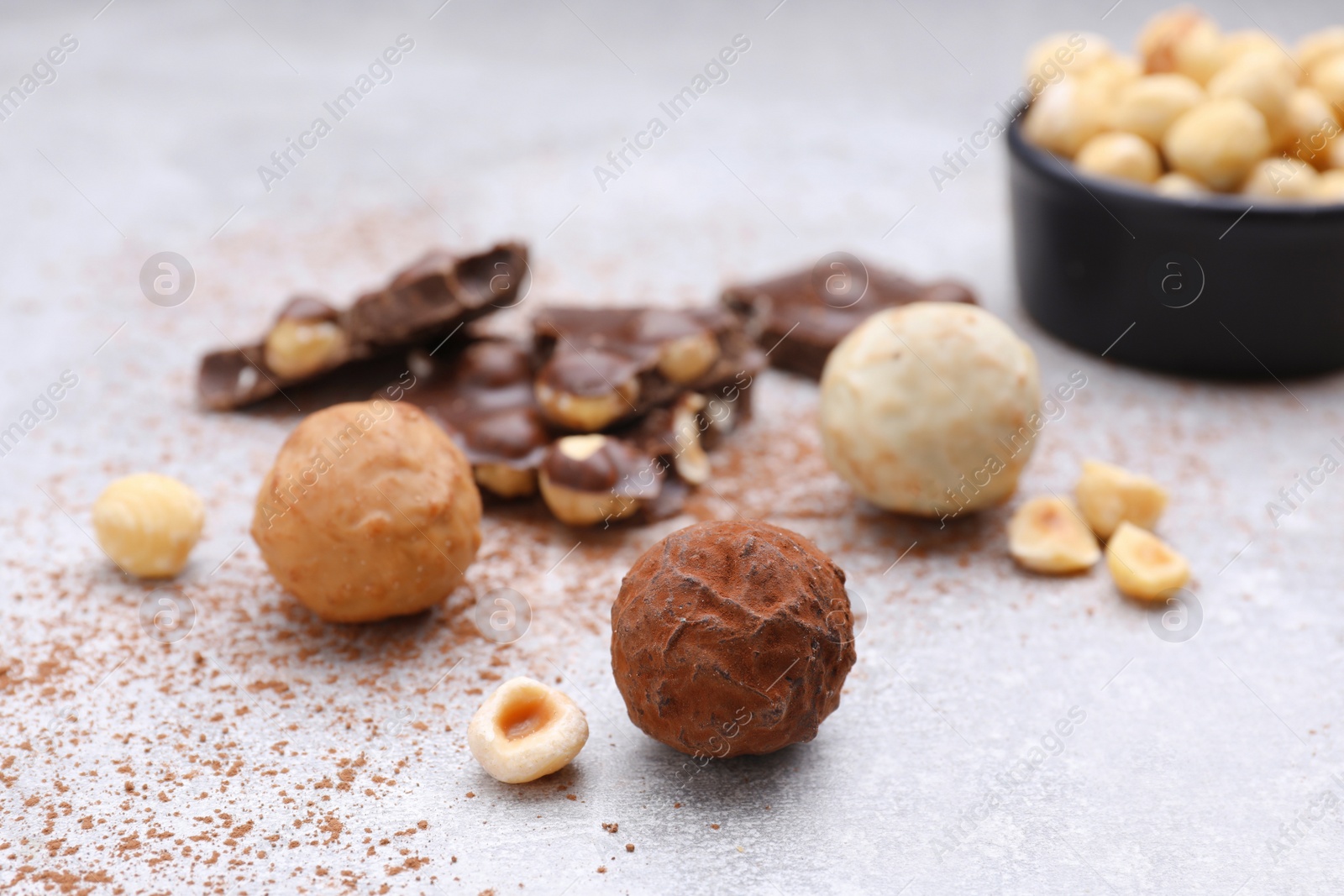 Photo of Tasty chocolate candies and nuts on light grey table
