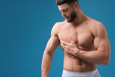 Photo of Handsome muscular man on light blue background, space for text. Sexy body