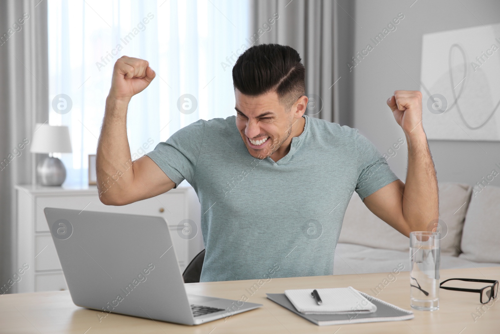 Photo of Emotional man participating in online auction using laptop at home