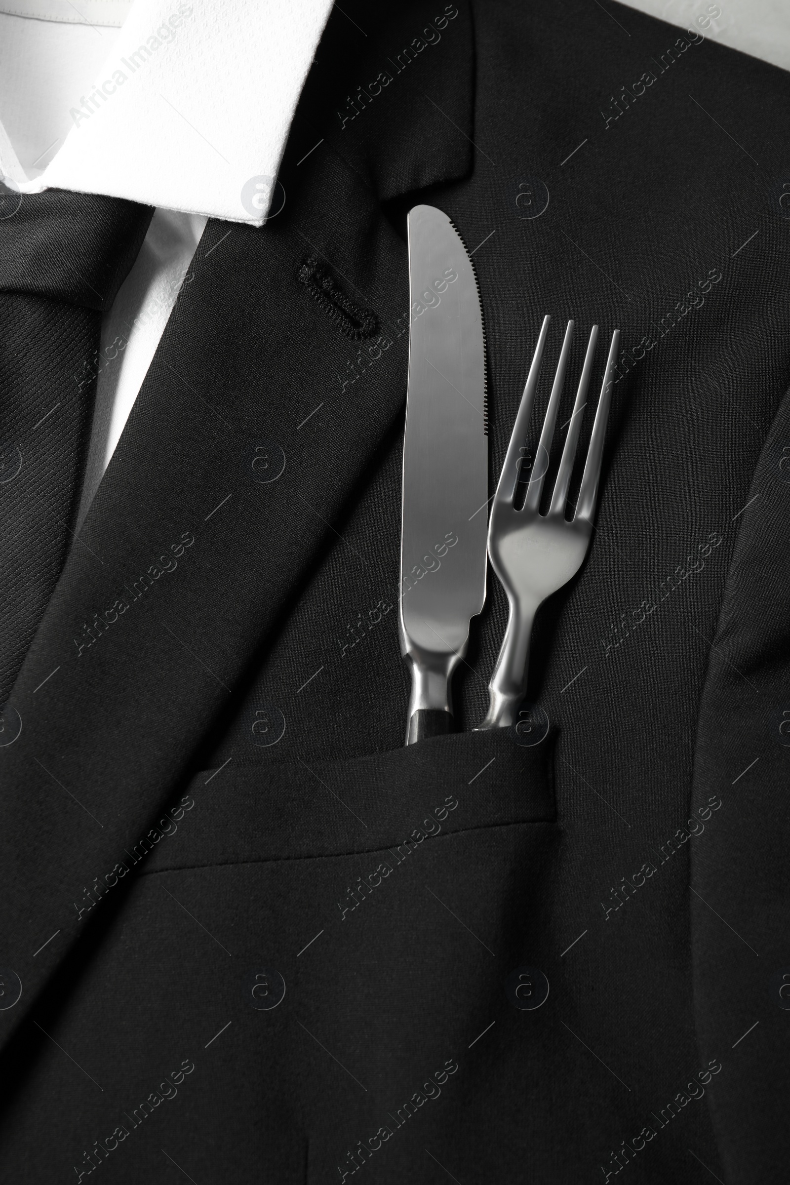 Photo of Man's jacket with cutlery as background, closeup. Business lunch concept