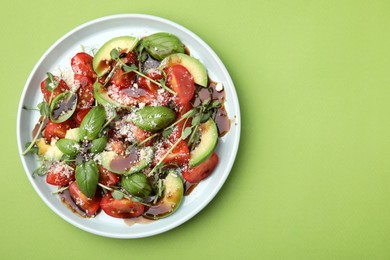 Photo of Tasty salad with balsamic vinegar on light green background, top view. Space for text