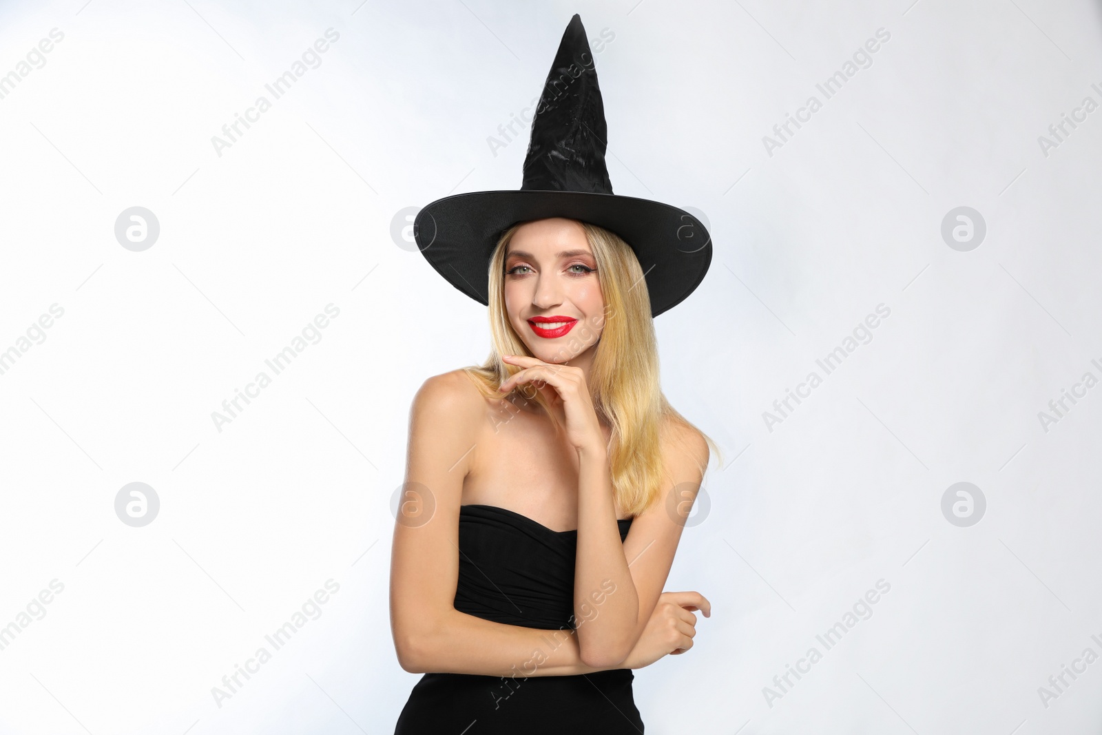 Photo of Beautiful woman in witch costume on white background. Halloween party