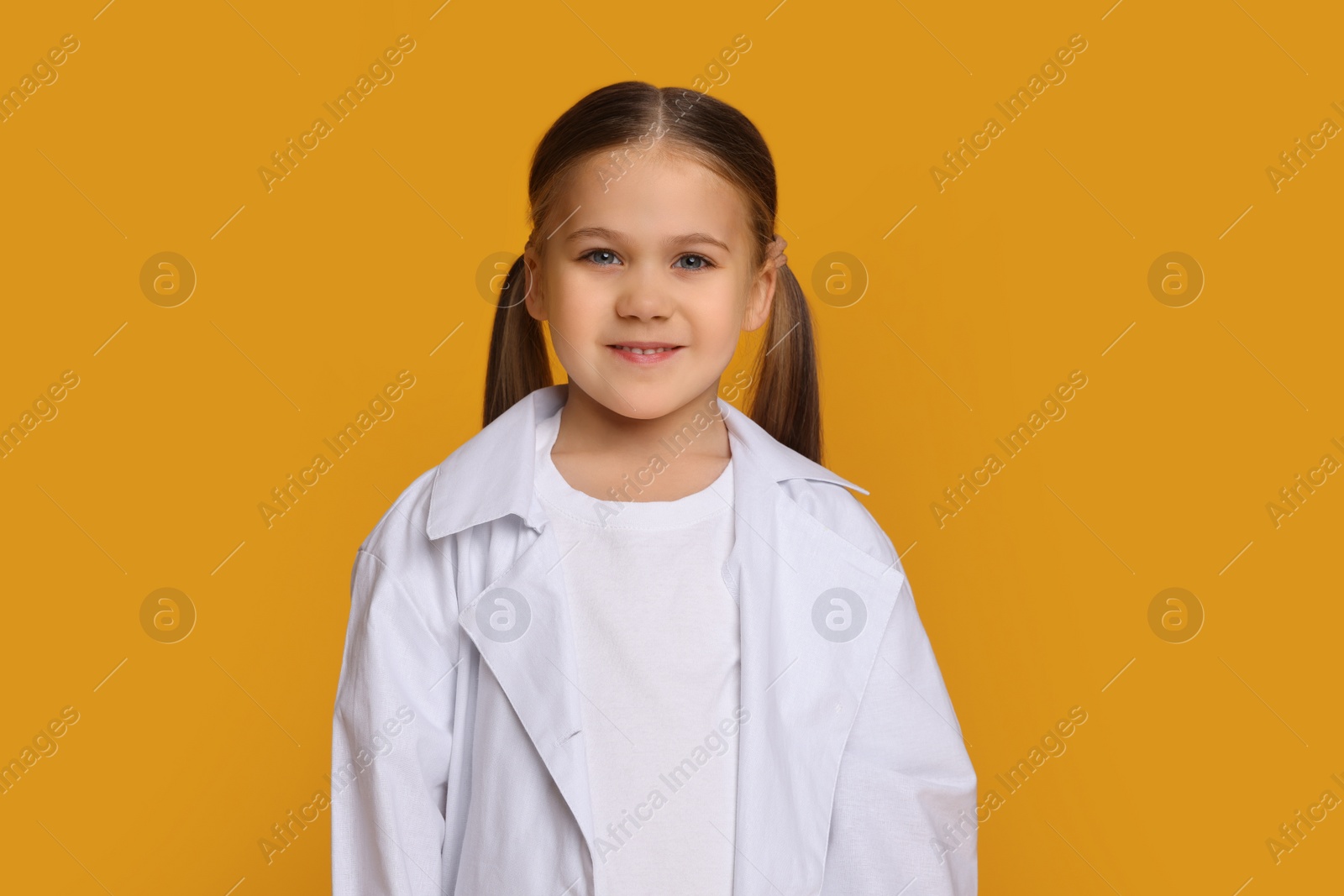 Photo of Portrait of little girl in medical uniform on yellow background