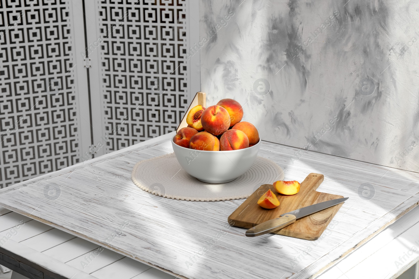 Photo of Bowl of juicy peaches and double-sided backdrop on table in photo studio