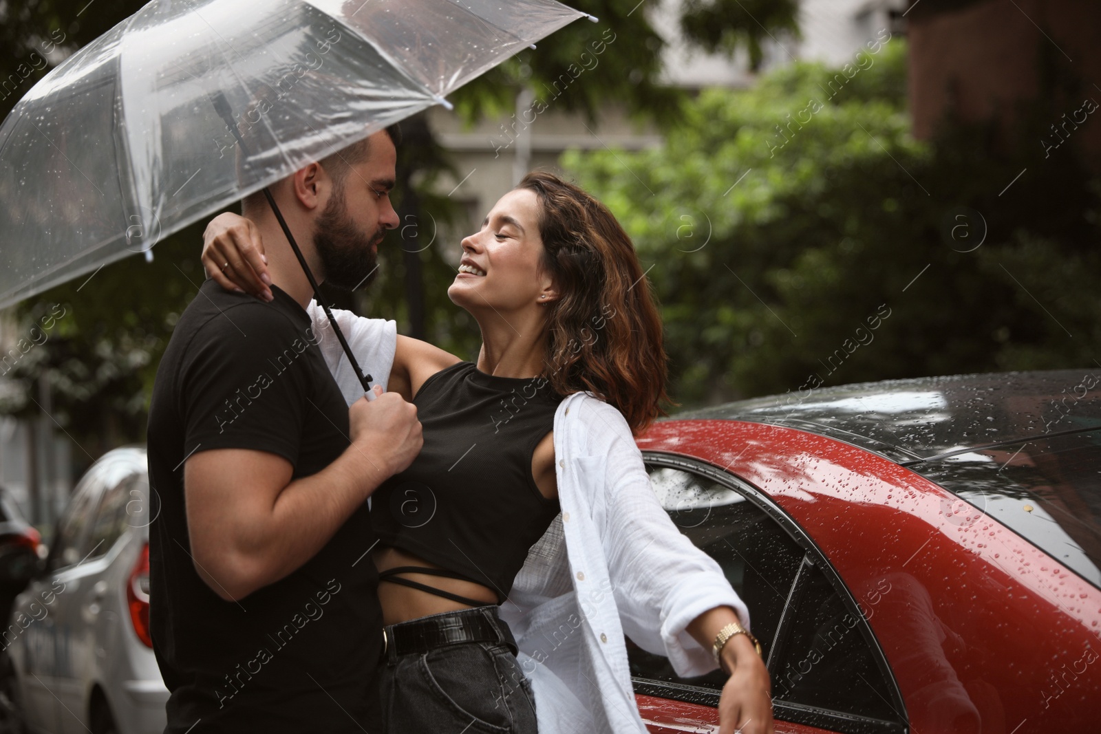 Photo of Young couple with umbrella enjoying time together under rain on city street, space for text