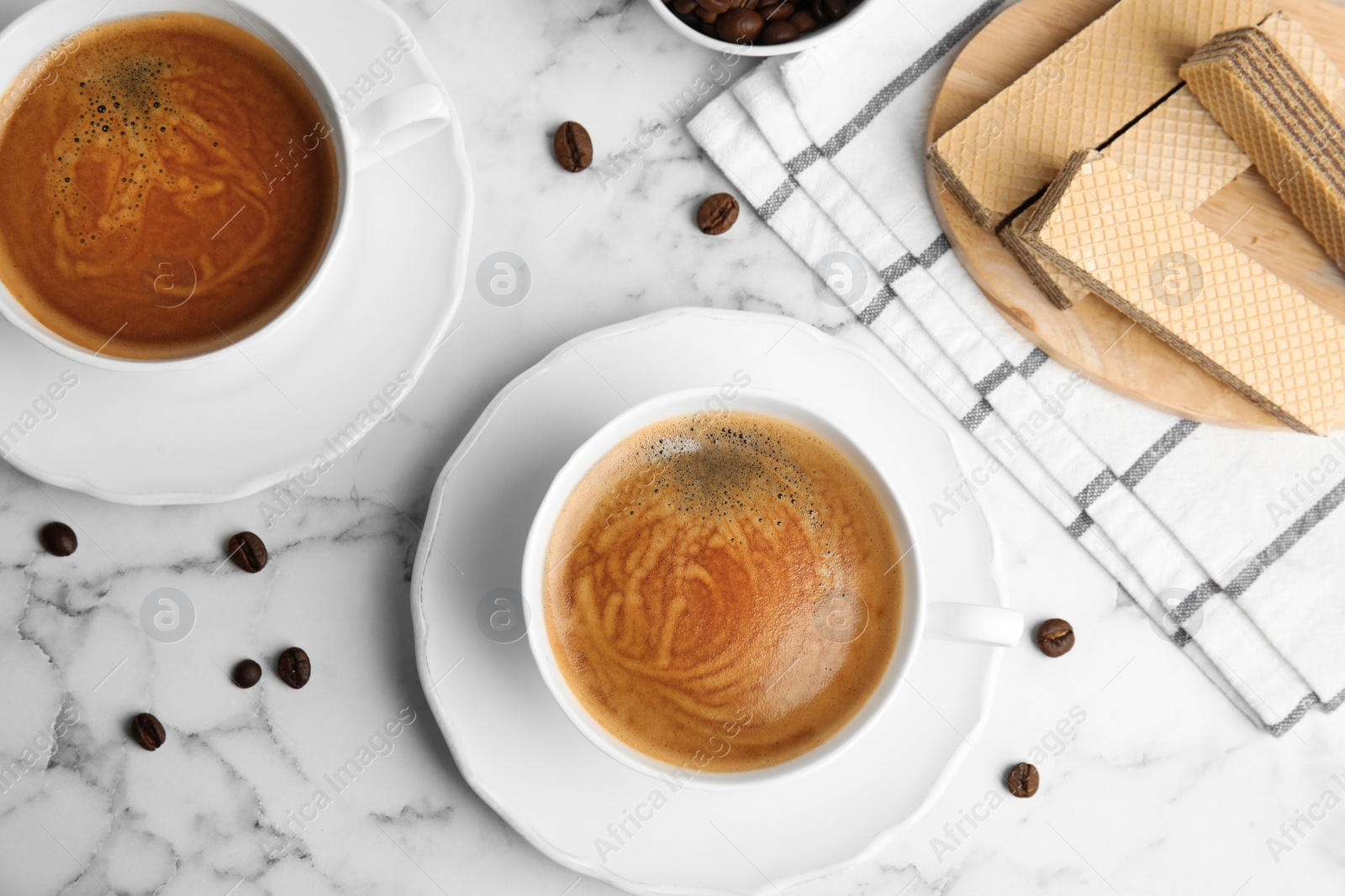 Photo of Delicious wafers and coffee for breakfast on white marble table, flat lay