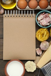 Blank recipe book and different ingredients on wooden table, flat lay. Space for text