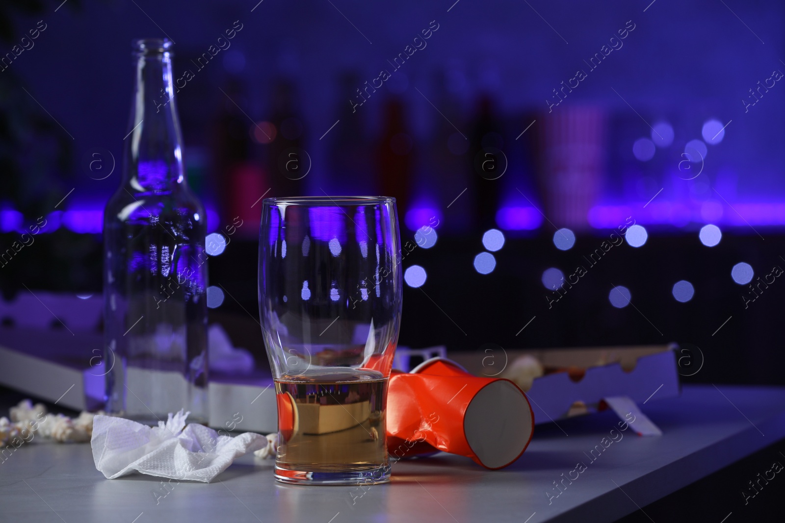 Photo of Messy table with beer and pizza box indoors, space for text. After party chaos