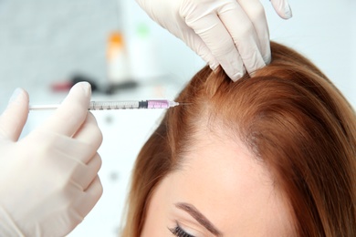 Photo of Young woman with hair loss problem receiving injection in clinic, closeup