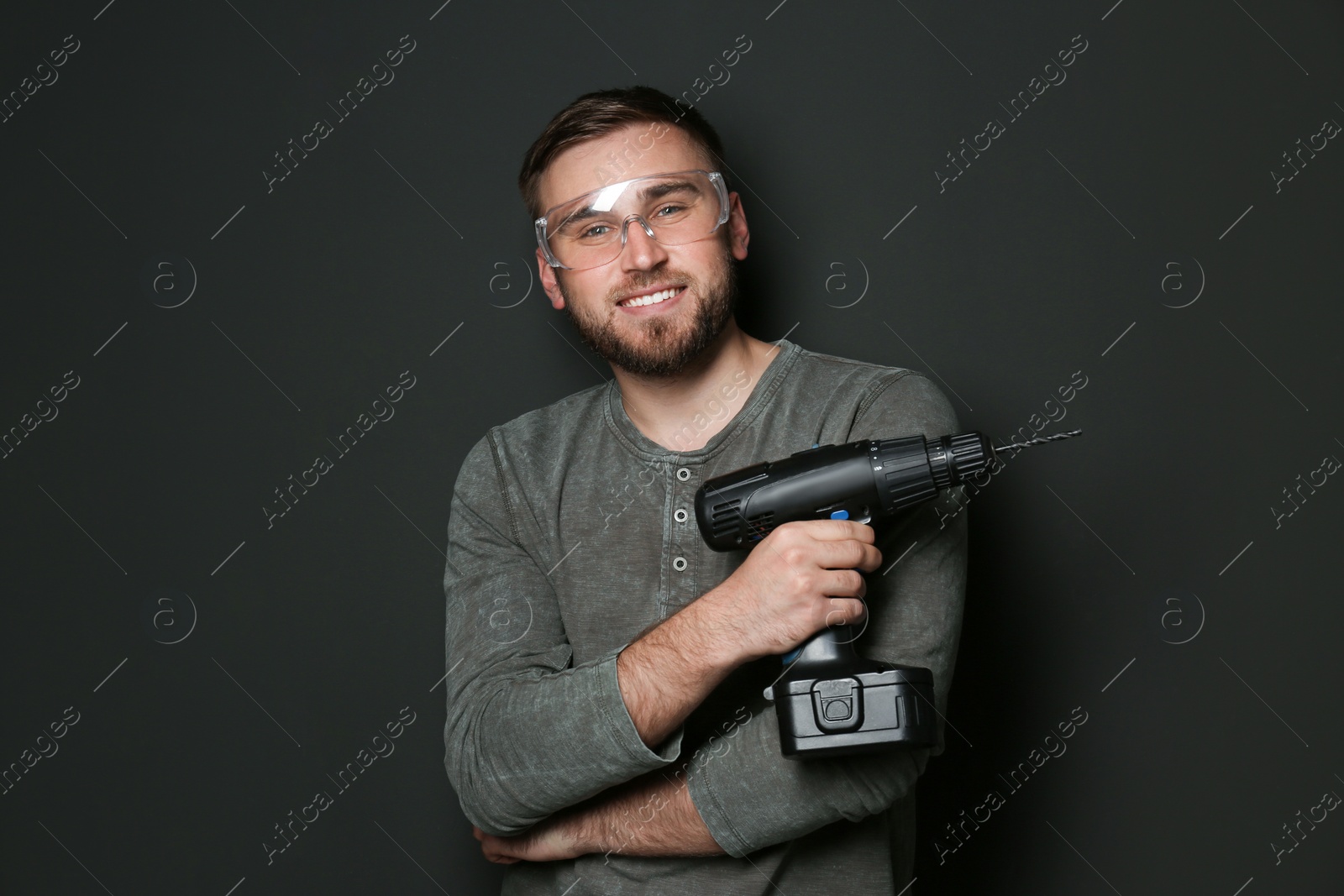 Photo of Young working man with power drill on dark background