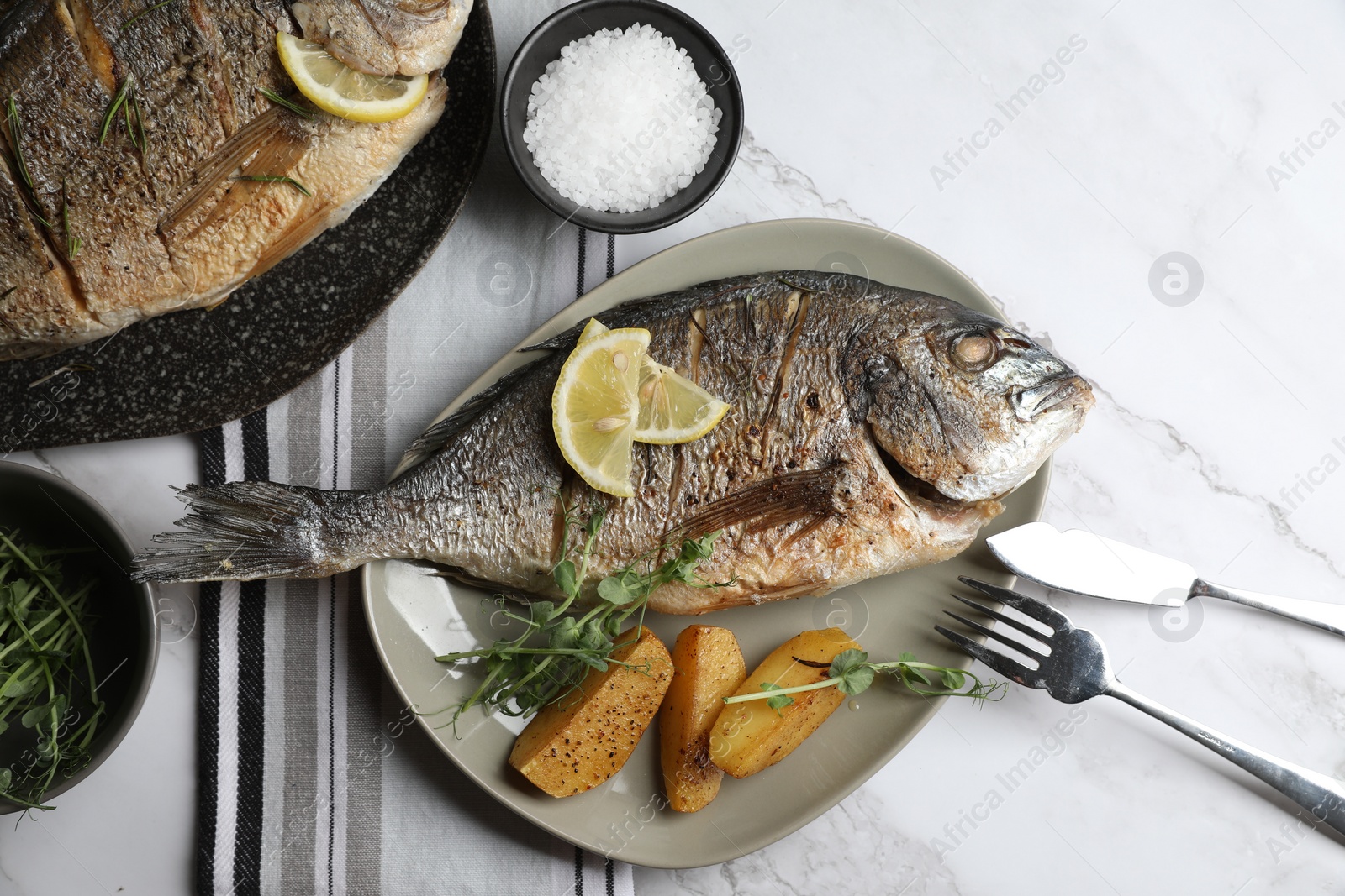Photo of Seafood. Delicious baked fish served on white marble table, flat lay