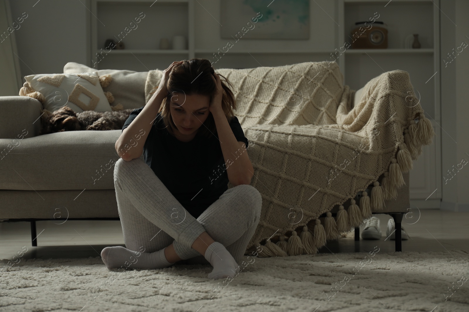 Photo of Sad young woman and her dog at home