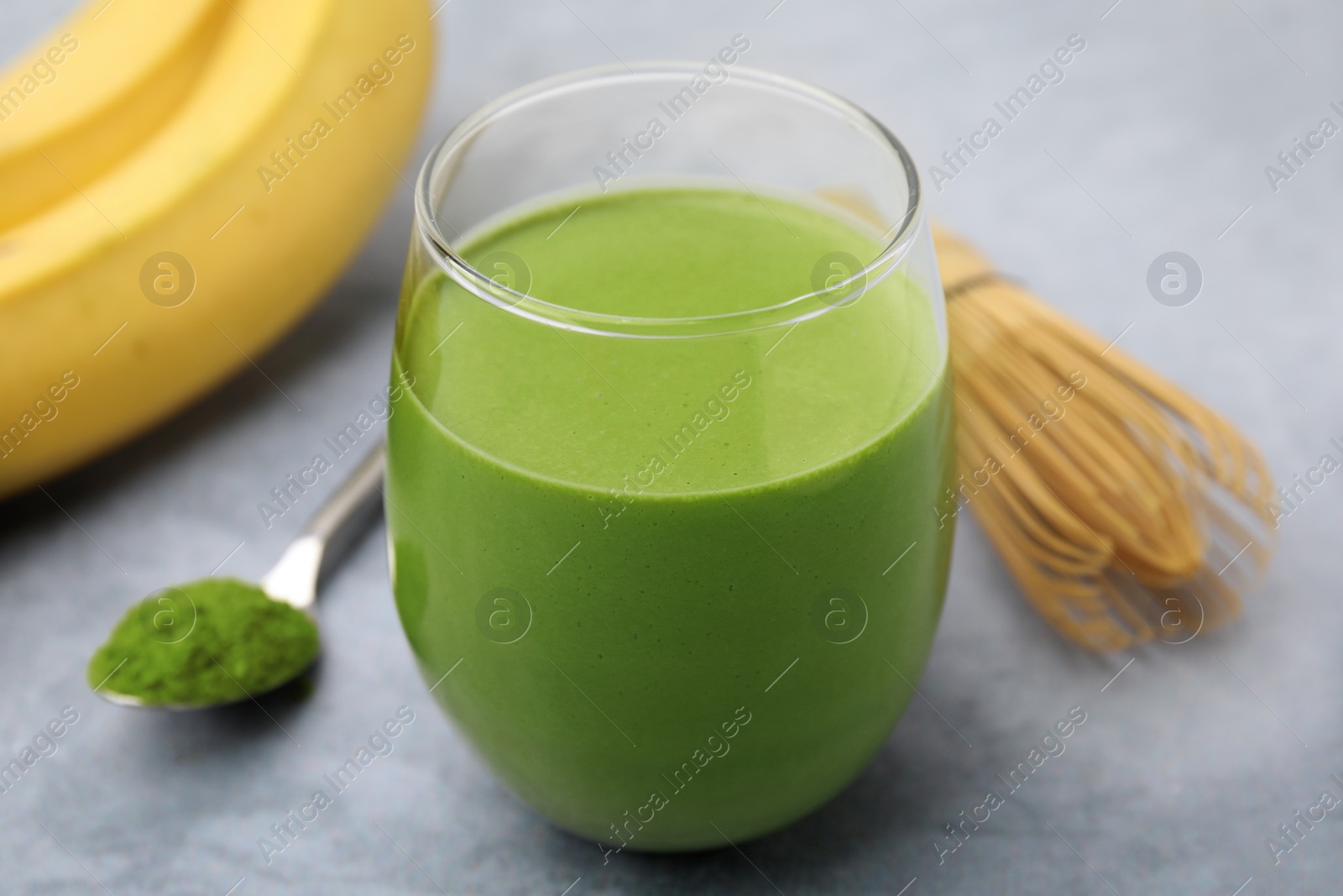 Photo of Glass of tasty matcha smoothie on light grey table, closeup