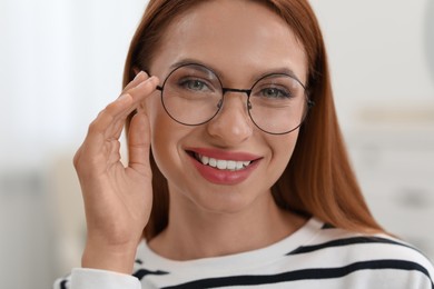 Portrait of beautiful young woman with red hair on blurred background. Attractive lady smiling and looking into camera