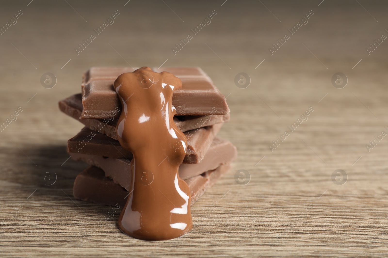 Photo of Pieces of milk chocolate with tasty paste on wooden table, closeup. Space for text