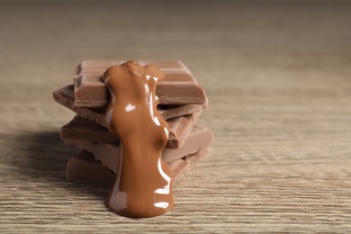 Pieces of milk chocolate with tasty paste on wooden table, closeup. Space for text