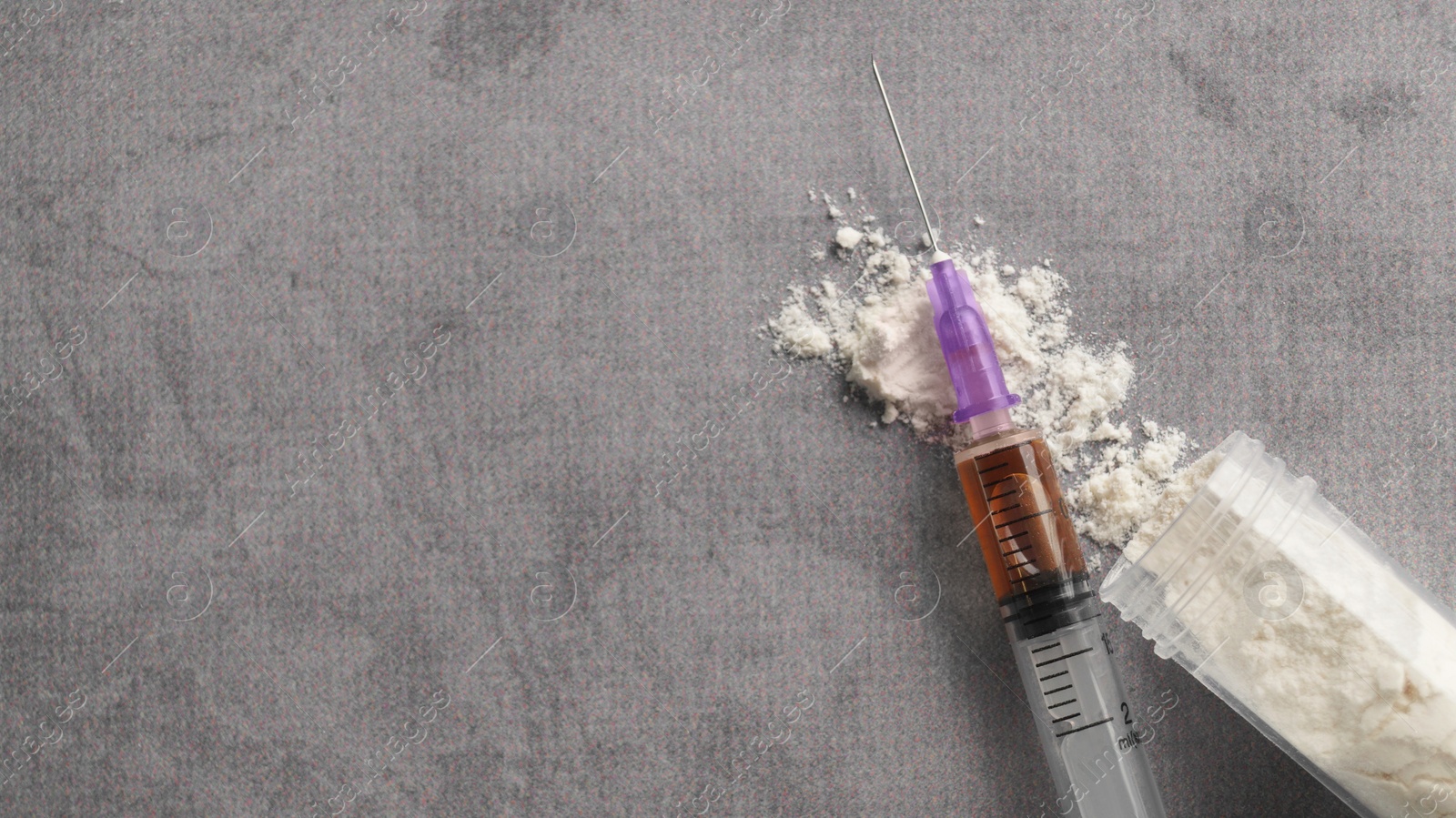 Photo of Plastic container of powder and syringe on grey table, flat lay with space for text. Hard drugs