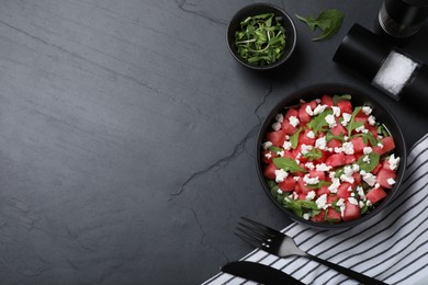 Photo of Delicious salad with watermelon, arugula and feta cheese served on black table, flat lay. Space for text