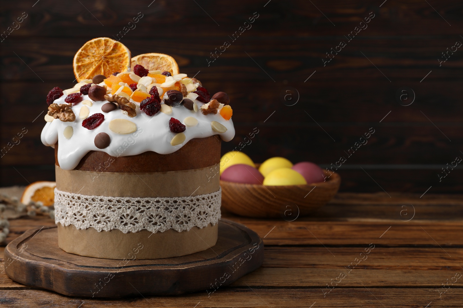 Photo of Delicious Easter cake with dried fruits and painted eggs on wooden table. Space for text