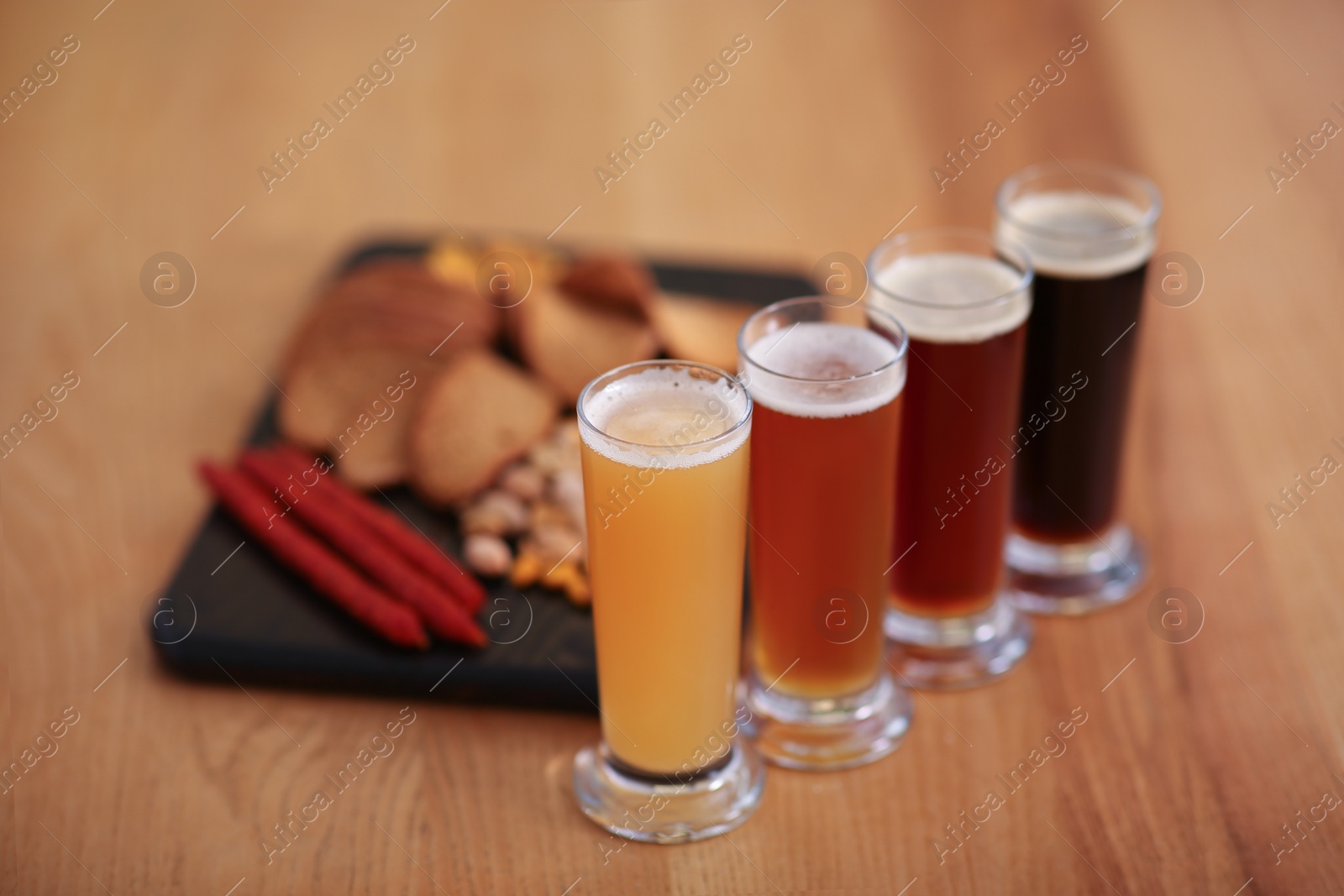 Photo of Beer tasting set served with snacks on wooden table