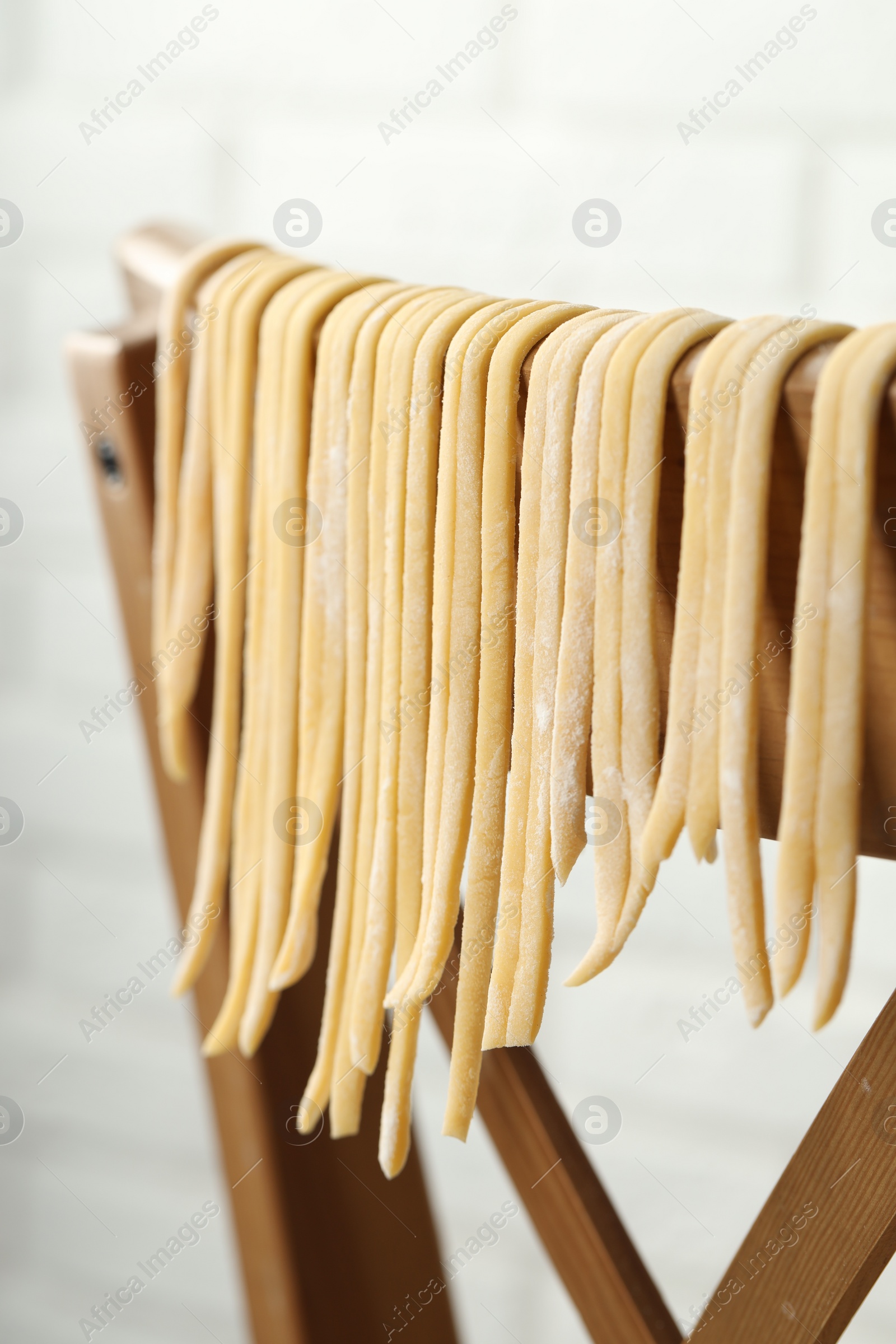 Photo of Homemade pasta drying on chair against white background, closeup